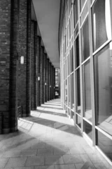 Foto op Canvas Urban modern street photography of architecture in Hamburg at a curved path between columns and glass windows and shadows on the ground © Felix