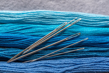 detalle de madeja de hilo para bordar en azules degradado con agujas y tijeras 