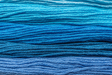 detalle de textura de madejas de hilo para bordar en degradado de azules cenital