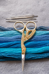 detalle de madeja de hilo para bordar en azules degradado con agujas y tijeras 