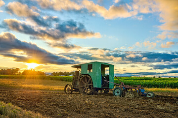 Steam engine plows rural Indiana farm field at sunset.
