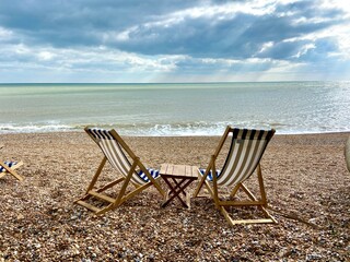 summer beach Deck chairs on seaside beach of summer seaside Hastings East Sussex Uk, sea sky and ocean waves behind