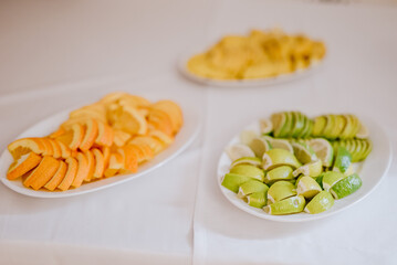 Cytryny, pomarańczki i limonki na białym talerzu 
