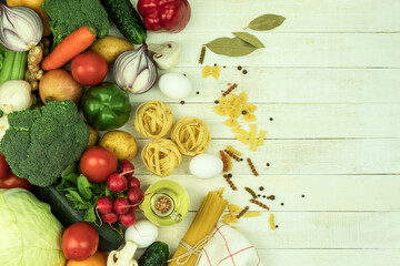 Raw pasta of various types and spices on a wooden table