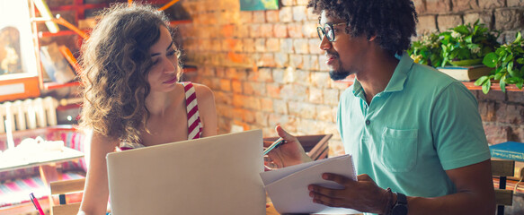 Woman and man students studying in the coffee shop using laptop.