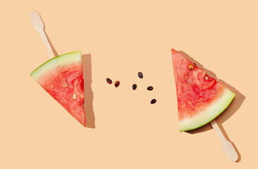 Piece of watermelon with a stick on orange pastel background