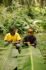 Portrait of two young african male kids playing in the african rainforest