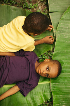 portrait of two young african boys playing and laying down in the african rainforest
