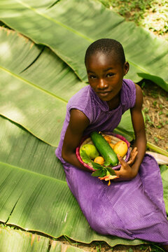 Portrait of a young african farmer holding her harvest in the rainforest 