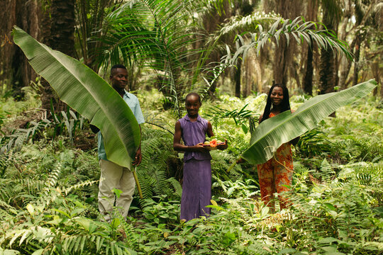 Family of african farmers of different ages holding their crop in the african rainforest