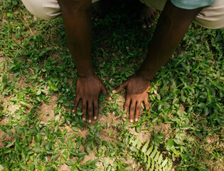 Fototapeta premium Portrait of a black african nature activist placing his hands in the soil 