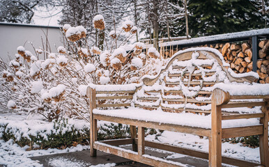 Ławeczka w ogrodzie w zimowy śnieżny dzień. Miejsce do odpoczynku w nowoczesnym ogrodzie - obrazy, fototapety, plakaty
