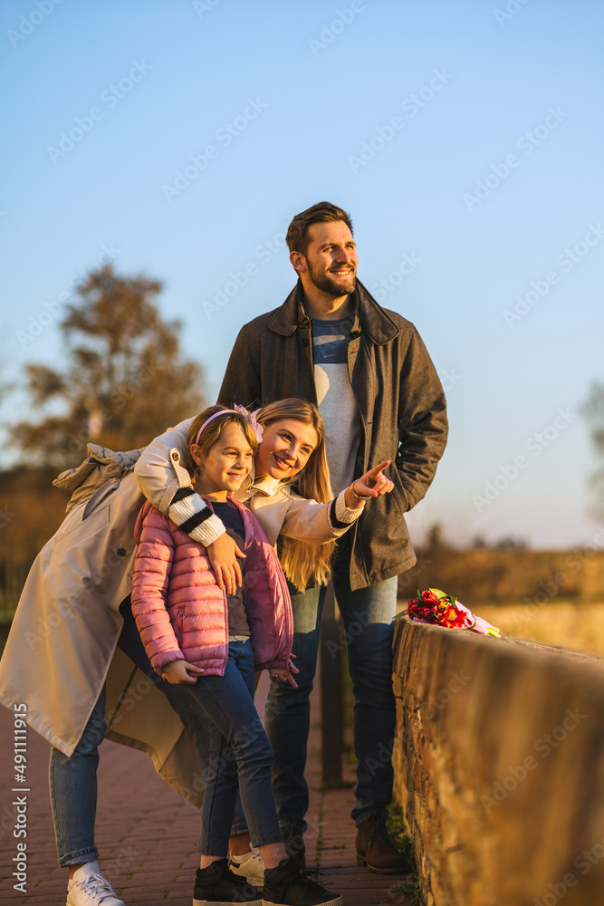 Wall mural a happy family stands on a fortress overlooking the city and the river. they enjoy a beautiful day a