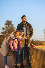 Fototapeta premium A happy family stands on a fortress overlooking the city and the river. They enjoy a beautiful day and a view.