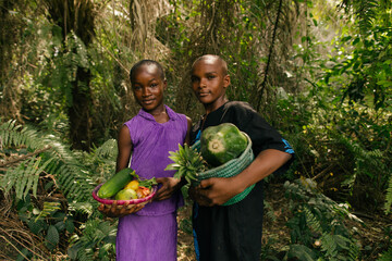 Portrait of young black african farmer siblings holding their baskets of fruits in nature 