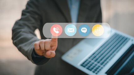 Contact us or the connected customer support hotline. Businessman using laptop and tapping contact icon on virtual screen, phone, email, address, live chat, internet, available 24 hours a day.
