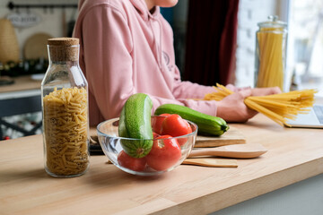 Teenage boy watching on laptop video recipe pasta spaghetti with vegetables. cooking courses online, italian cuisine tutorial	