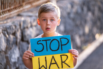 Child against war. Upset Ukrainian boy with blue yellow flag with stop war sign , protesting war...
