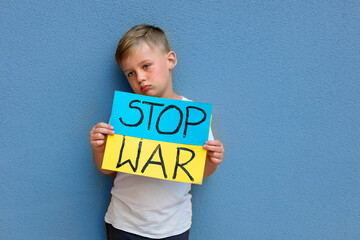 Child against war. Upset Ukrainian boy with blue yellow flag with stop war sign , protesting war...