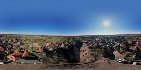 Above church tower airscape 360 degrees panorama of small town Geesteren farms in rural Dutch countryside townscape with bright clear blue sky. Equirectangular projection ready for VR 3D use.