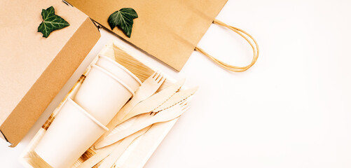 Recycling,eco-friendly concept.Disposable eco cutlery,plates,spoons,knives,forks on a light background.Craft paper bag for food delivery.Copy space.Eco craft paper tableware,cups,fast food containers.