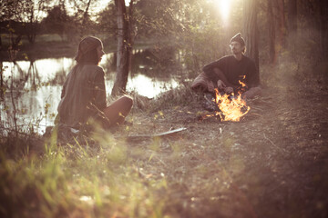 friends talk around fire in natural light by water