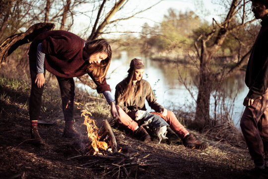Young strong alternative friends make a fire riverside