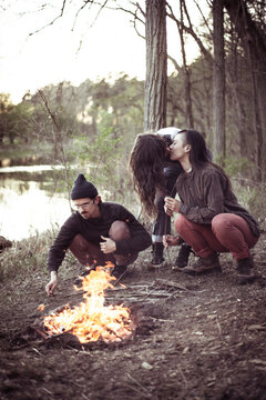 gay couple kiss by fire and river with friends