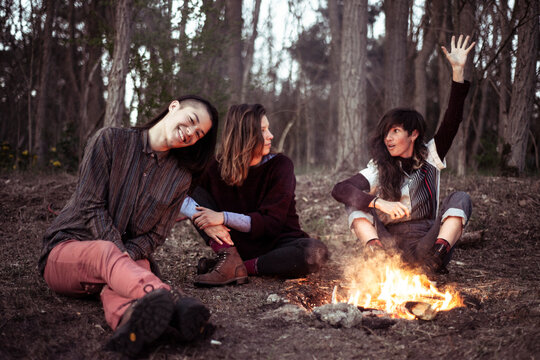 female friends chatting around campfire in forrest