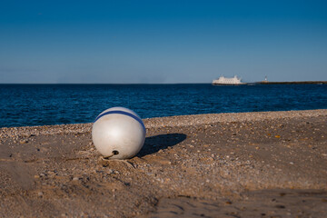 Obraz premium A lonely buoy on the beach with a ship in the distance in the evening