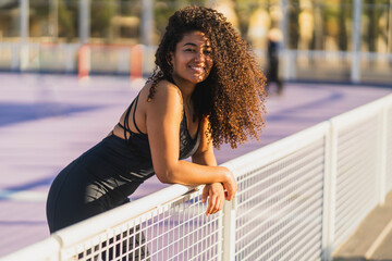 Chica marroquí morena con pelo largo rizado posando y colocándose el pelo en una barrera de...