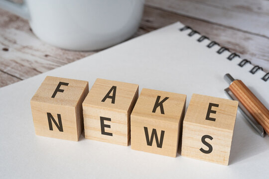 フェイクニュースのイメージ｜「FAKE」「NEWS」と書かれた積み木、ペン、ノート、コップ