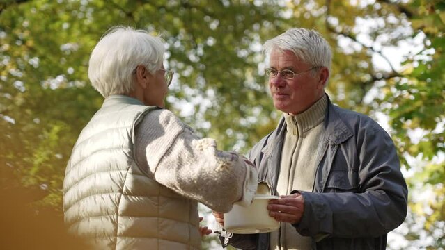 Caucasian elderly retired woman shares her homemade soup with jobless and homeless elderly man in need. High quality 4k footage