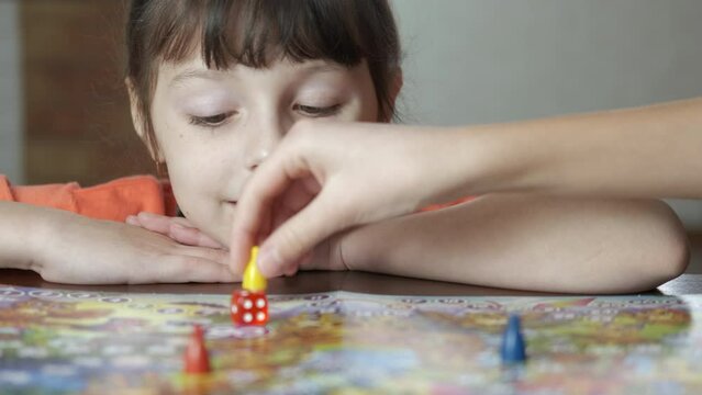 Happy child with board game. A happy child play with her mother with a boad game in the room.