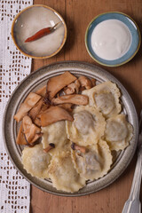 Round dumplings, ravioli with meat on a plate, fried mushrooms. Sauce and hot peppers on saucers