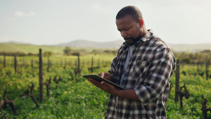 Farming just got a whole lot more efficient. Shot of a mature man using a digital tablet while...
