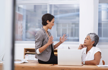 Sharing her strategy. Shot of two coworkers having a discussion in the office.