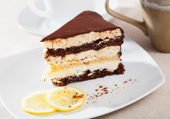 Slice of delicious chocolate lemon cake served on white plate with sliced lemon ..