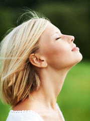 Letting the breeze blow her cares away. Gorgeous young woman savoring the breeze outdoors - profile.