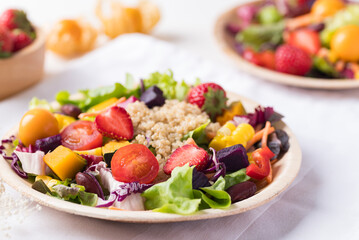 Fresh mixed fruits and vegetables salad in natural plate on white background, Healthy vegan food