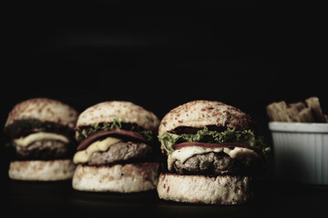 Three mini burgers on black background