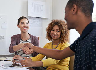 Were eager to see what you can offer our business. Shot of coworkers shaking hands during a meeting in a modern office.