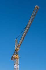 A tall construction crane standing against a bright blue sky
