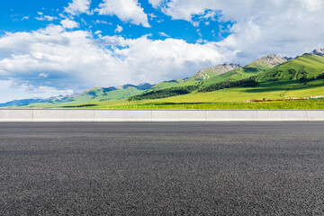 Empty asphalt road and green mountain nature scenery under blue sky
