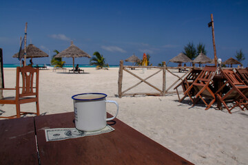 metal mug against the background of the sea on a hundred dollar bill