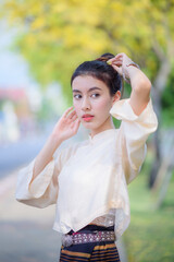 Beautiful smiling asian woman in traditional lanna style dress with blooming Golden shower flower, Chiang mai, Thailand