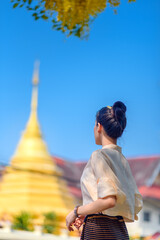 Beautiful smiling asian woman in traditional lanna style dress with blooming Golden shower flower, Chiang mai, Thailand