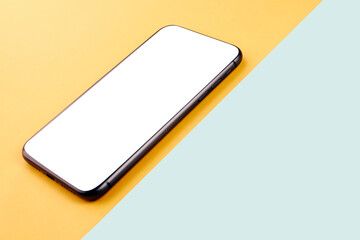 Phone mockup with copy space and white screen on top of yellow and teal contrast table
