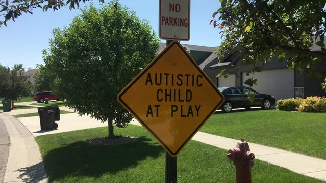 Autistic child at play sign in residential neighborhood; partially shaded on bright summers day.