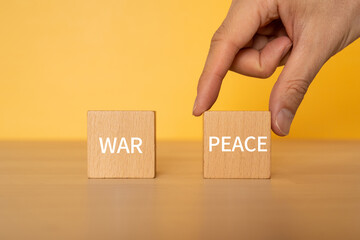 平和のイメージ｜「WAR」「PEACE」と書かれた積み木と手